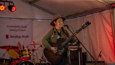 Performer Felicity Dowd, with guitar, singing on stage