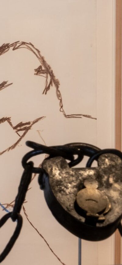 Installation image of convict cuffs with artworks by Sidney Nolan in background