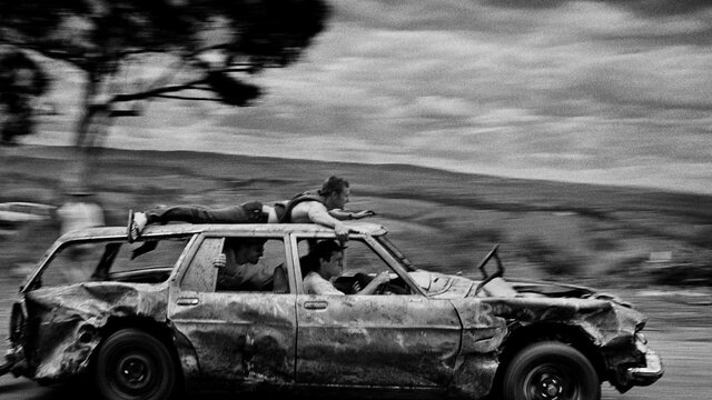 Trent Parke, Untitled #4 1998, from the series ‘Mount Pandemonium, Bathurst, NSW’, National Gallery black & white image of a banged-up car speeding past with passengers and one man on the car roof