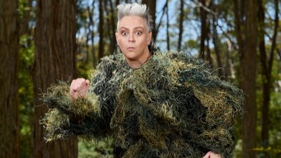 Woman in a ghillie suit running through the forest