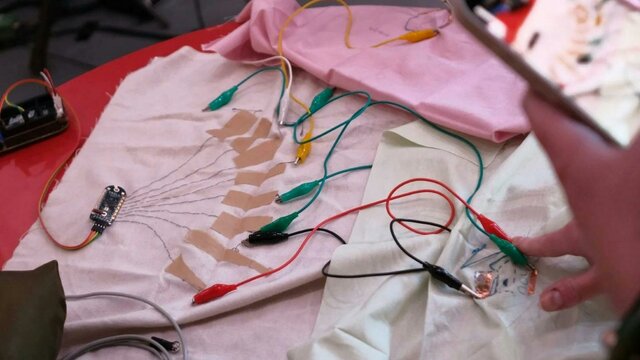 Amplified Textiles Workshop 2025 A photo of some textile fabric swatches with electrical nodes and cords attached
