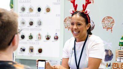 Woman from Love Dem Apples serving a customer whilst wearing Christmas reindeer antlers