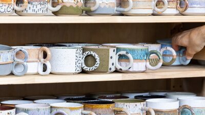 Colourful ceramic mugs sitting on shelves