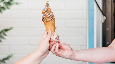 Future Swirl oat milk soft serve in a cone being handed to customer