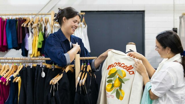 Al Elé Al Elé showing a customer a jacket