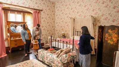 A family and tour guide in a bedroom during a Lanyon Homestead tour