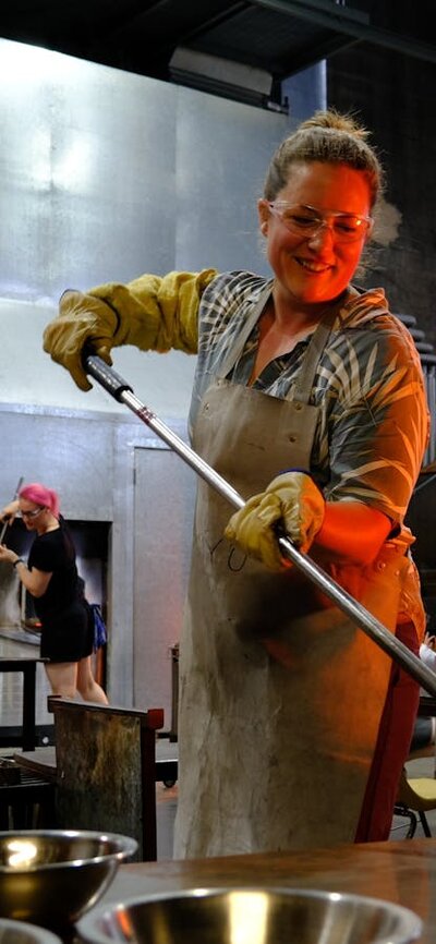 Participant in the Glassworks hotshop working with molten glass