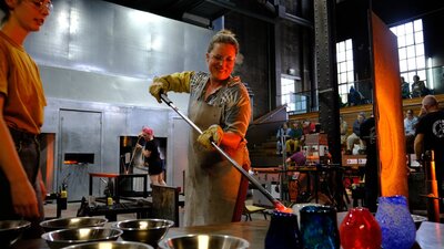 Participant in the Glassworks hotshop working with molten glass