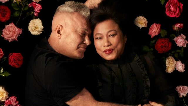 Two adults embracing on a bed of roses.