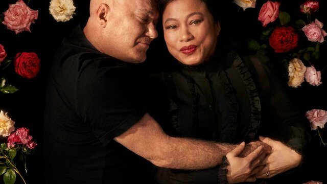 Two adults embracing on a bed of roses.