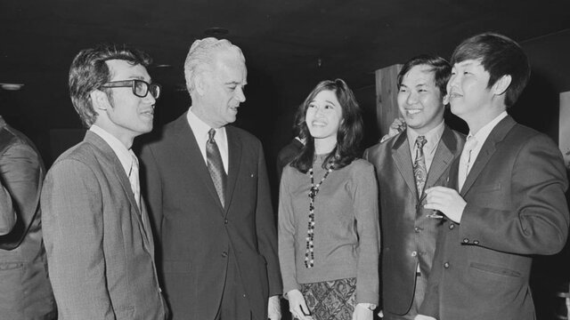 Image courtesy of the National Archives of Australia. NAA: A6180, 28/8/72/59. Four men and a woman in conversation while wearing business attire.