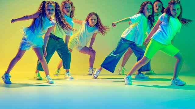 Image of young girls dancing with coloured lighting in background