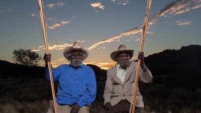 Two first nations elders in sitting in country near Amaroona at sunset with hand carved spears