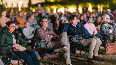 Crowd looking on, watching film festival in outdoor venue