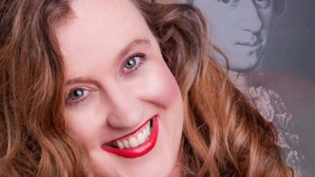 Fleur Millar A portrait of a smiling woman with wavy brown hair and bright red lipstick.