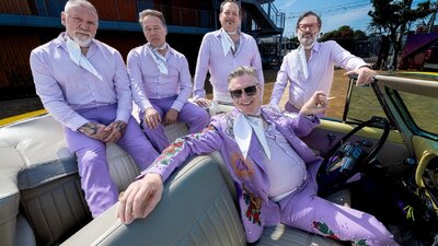 Group of men sitting on and in a car wearing purple