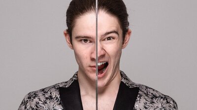 A man in a silver jacket standing with two different facial expressions split by a sword.