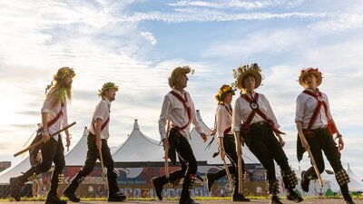 6 Morris Dancers perform in Traditional Costume with a big-top tent in the background