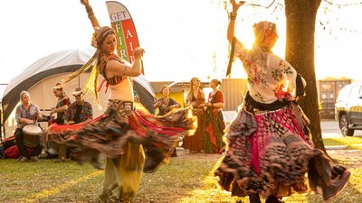 2 woman dressed in traditional Turkish dresses dance for a crowd