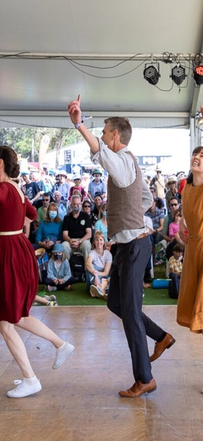 Dancers at the National Folk Festival 7 people dressed in bring colours perform a dance for a crowd