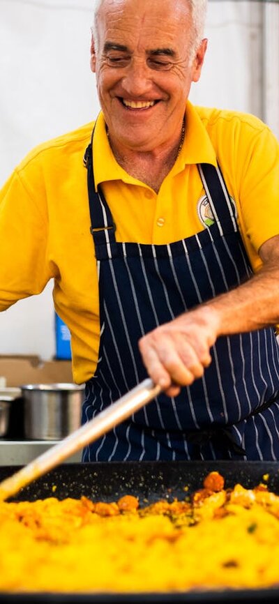 A man cooking paella in a large frying pan