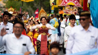 A woman wearing a cultural headpiece and carrying a gold dish in the festival parade