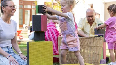 A young girl building a tower with large blocks.