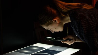 Person exploring glass plates with stars in Outer Space exhibition