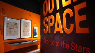 Outer Space exhibition wall with text and objects in distance