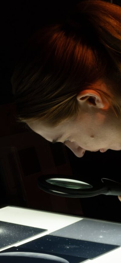 Outer Space: Stromlo to the Stars Person exploring glass plates with stars in Outer Space exhibition