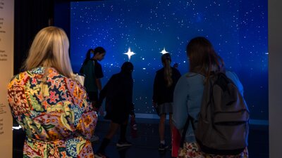 Gravitational Weave, a digital interactive representing the growth of our universe. Young people interacting with Gravitational Weave at Outer Space