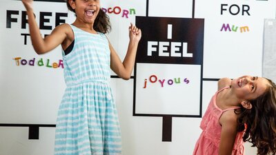 Two girls laughing at interactive letter wall in MoAD’s PlayUP exhibition space