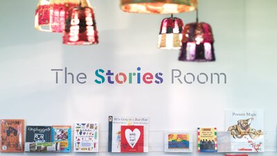 Colourful lamps and shelves of books in The Stories Room space
