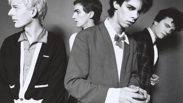 The Boys Next Door, 1978 Michel Lawrence. © Michel Lawrence A monochrome photographic portrait of four men with candid expressions wearing suits.