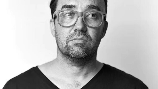 Gabriel Clark A sepia portrait of a man with glasses, looking slightly upward and to the side.