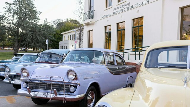 Photograph of pastel coloured classic Holden cars parked on display in front of NAA canberra