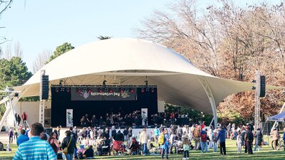 Crowd gathered at an outdoor Reconciliation Day event at Stage 88 watching a performance.