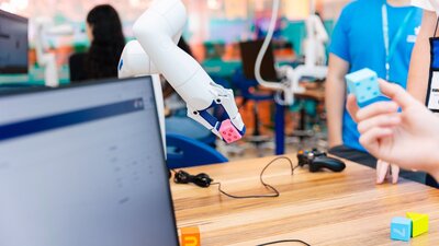 A robotic arm picks up a pink dice.