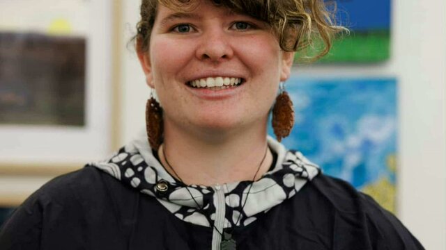 Kristal Matthews A smiling woman with curly brown hair and large brown earrings, wearing a black jacket.