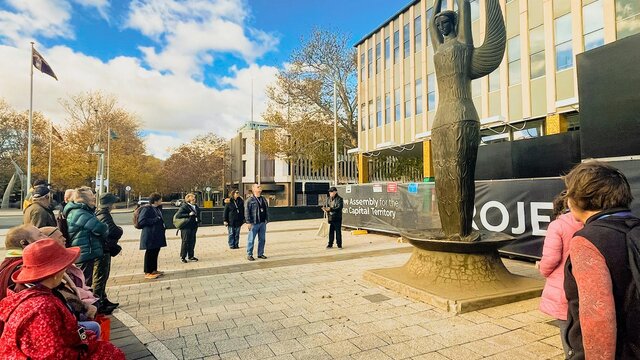 A walking tour group stands in front of the Ethos sculpture at ACT Legislative Assembly