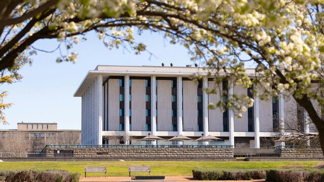 The National Library of Australia building with park benches and trees in the image.