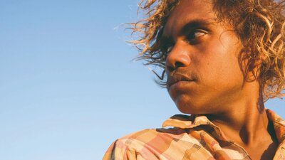 A close up of an adolescent boy looking over his right shoulder