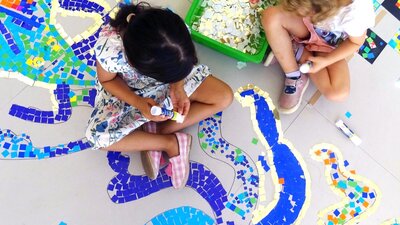 Children sitting and creating a mosaic artwork