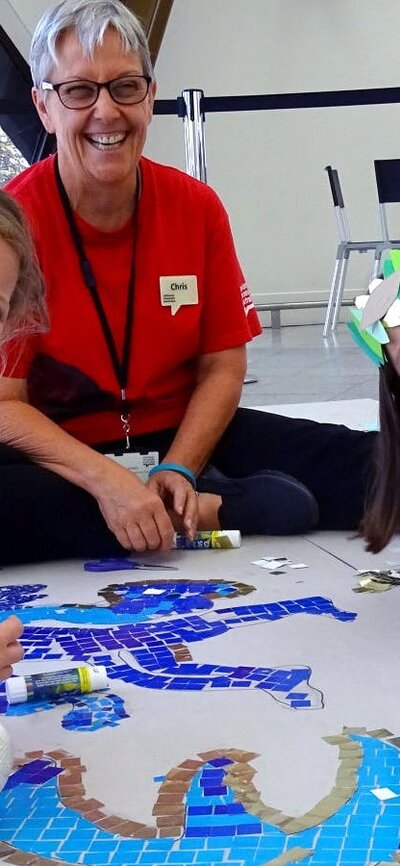 Children sitting with a museum host with a mosaic artwork