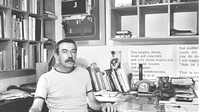 Enrico Taglietti in studio, 1985, photo by Ted Richards Enrico Taglietti holding a pen at his desk in his studio, photo taken in 1985