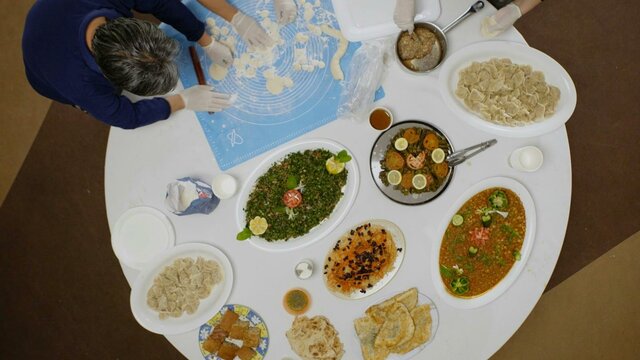 Gillian Kayrooz, 'From The Palm Of', 2024 Arial view of people around a round table full of platters of food