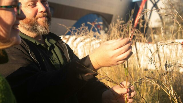 Adam Shipp Adam Shipp smiles as he holds native grasses outdoors during a guided cultural experience.