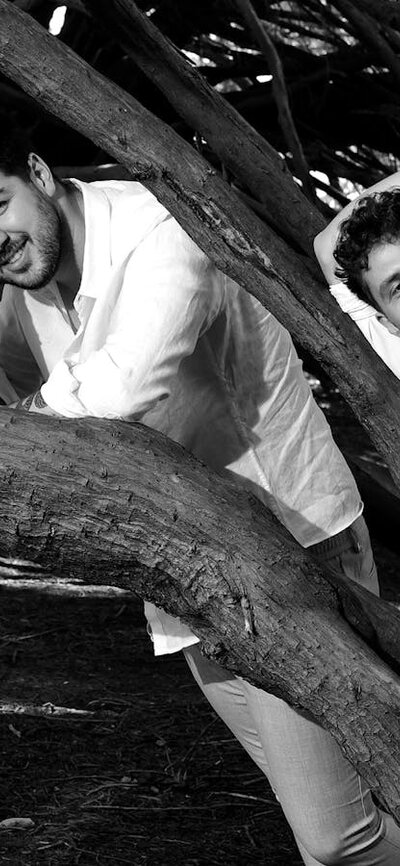 Three people standing amonst the branches of a tree in white clothing, looking at the camera