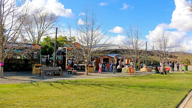 A landscape image shows a row of food vans and vendor stalls with lots of people of all ages
