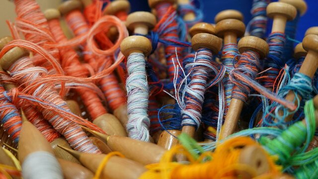 Photo courtesy of Australian Tapestry Workshop A close-up image of red and blue yarn on weaving bobbins